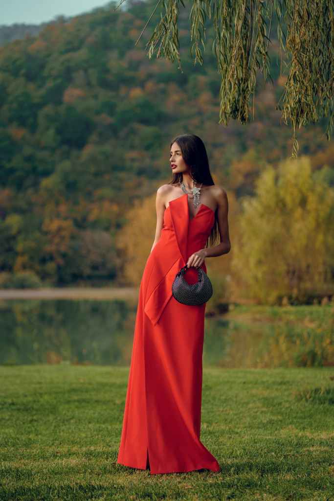 woman wearing monochromatic red colored evening gown and holding black colored clutch