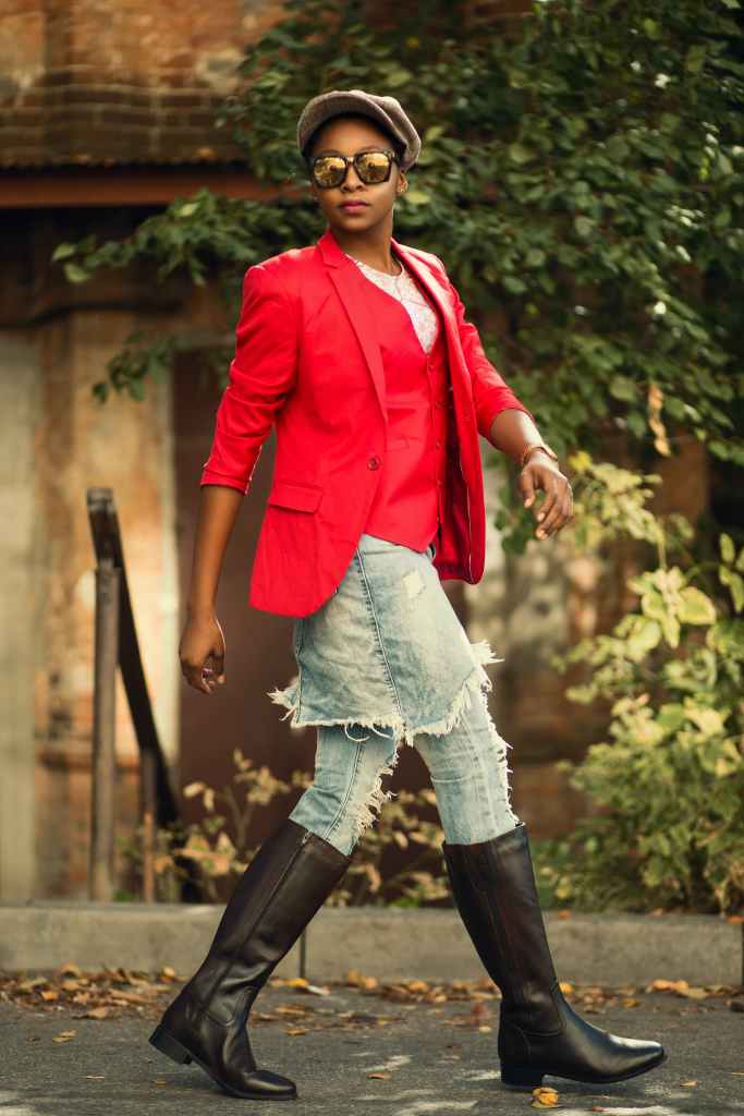 woman wearing red blazer with denim skirt and black boots.